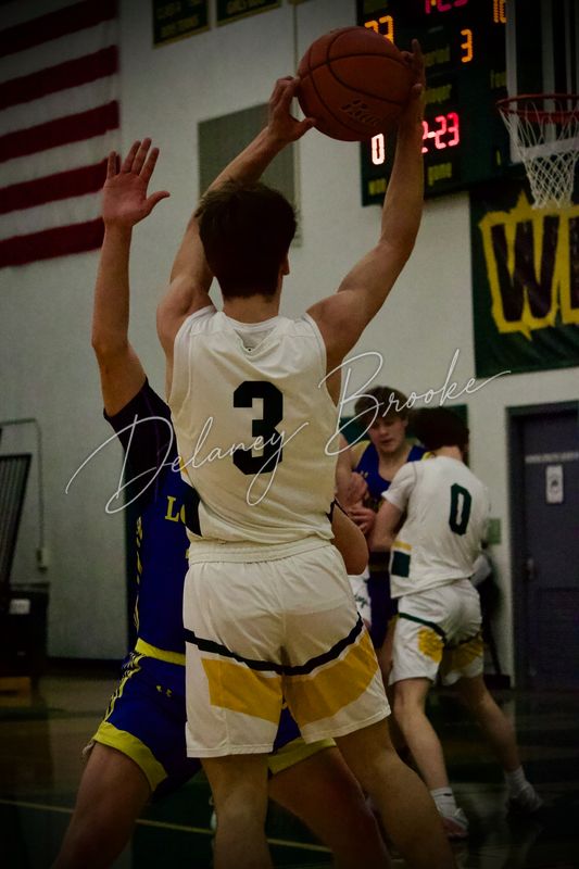 A basketball player pulling the ball down above his head as a defender reaching up to contest it.
